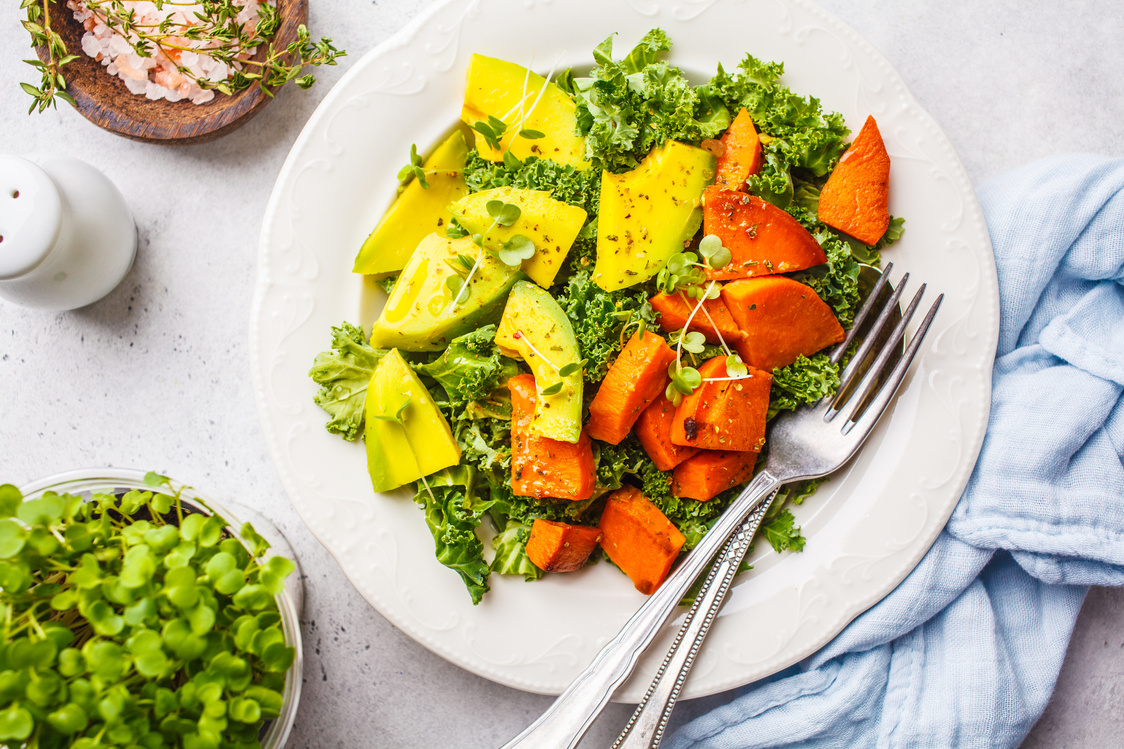 Healthy green kale salad with avocado and baked sweet potatoes. Plant based diet concept, detox food.